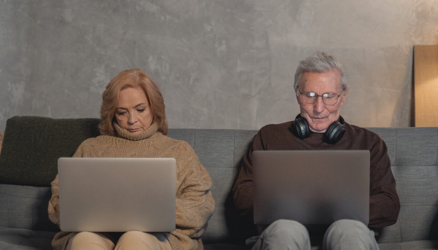 Woman in Brown Sweater Sitting on Brown Sofa Beside Man in Black Sunglasses