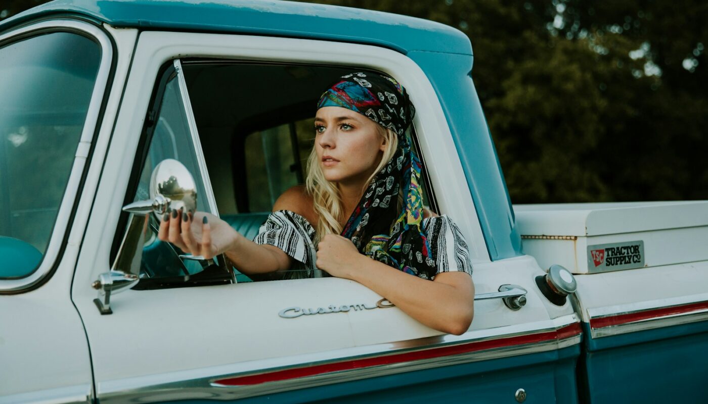 photography of woman holding side mirror in white and green 2-door pickup truck