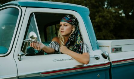 photography of woman holding side mirror in white and green 2-door pickup truck