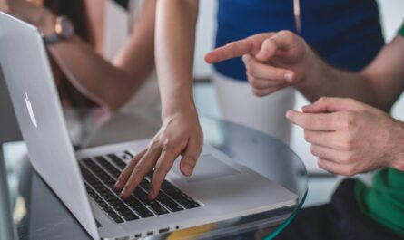 person touching and pointing MacBook Pro